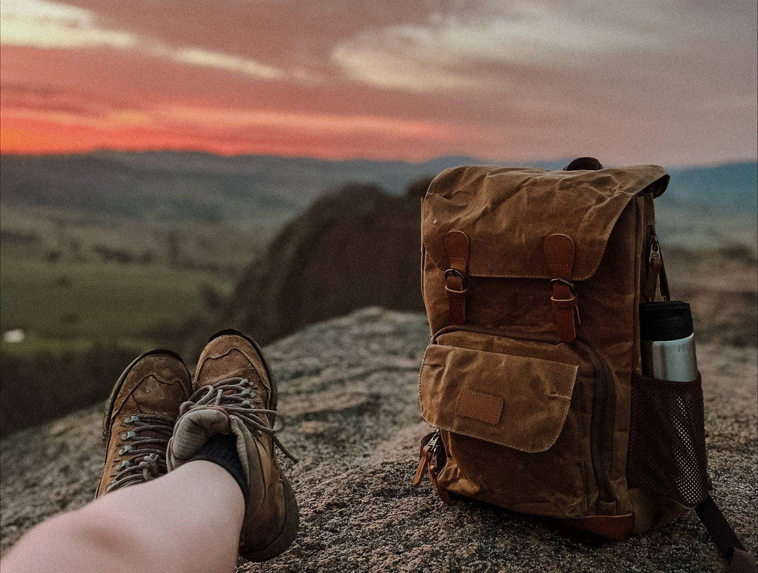 A hikers rests with their backpack next to their feet as they watch the sunrise